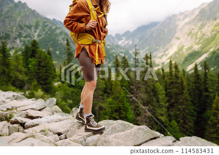 Hiking boot. Close-up of female legs in hiking boots on hiking trail, on top of mountain outdoors. Hiking boot. Close-up of female legs in hiking boots on hiking trail, on top of mountain outdoors. 114583431