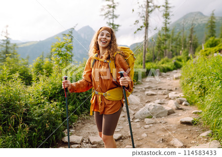 Stylish tourist woman with yellow backpack against backdrop of mountain scenery. Concept of travel. Stylish tourist woman with yellow backpack against backdrop of mountain scenery. Concept of travel. 114583433