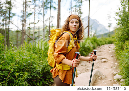 Stylish tourist woman with yellow backpack against backdrop of mountain scenery. Concept of travel. 114583440