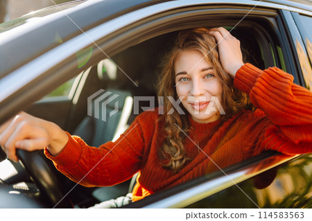 Young smiling woman driving a car drives around the city. Lifestyle concept. Young smiling woman driving a car drives around the city. Lifestyle concept. 114583563