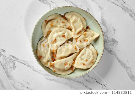 Savory vareniki with meat and crispy fried onions on ceramic bowl Savory vareniki with meat and crispy fried onions on ceramic bowl 114583811