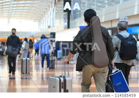 Airport Passengers: Passengers carrying musical instruments walking through the departure lobby at Haneda Airport Airport Passengers: Passengers carrying musical instruments walking through the departure lobby at Haneda Airport 114585459