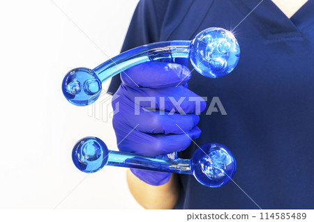Doctor Holds Blue Acrylic Back, Leg, Neck Massage Tool with Gloved Hand. Deep Tissue Massage, Thumb Massager with Knobs for Gentle Point, Muscles Relaxation. Horizontal Doctor Holds Blue Acrylic Back, Leg, Neck Massage Tool with Gloved Hand. Deep Tissue Massage, Thumb Massager with Knobs for Gentle Point, Muscles Relaxation. Horizontal 114585489