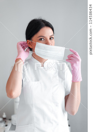 Cosmetologist putting on mask before beauty 114586434