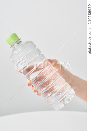 Woman's hand holding a plastic bottle of water 114586629