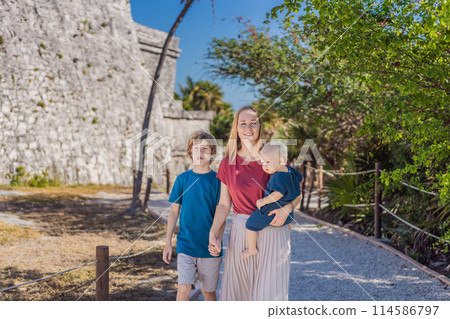 Mother and two sons tourists enjoying the view Pre-Columbian Mayan walled city of Tulum, Quintana Roo, Mexico, North America, Tulum, Mexico. El Castillo - castle the Mayan city of Tulum main temple 114586797