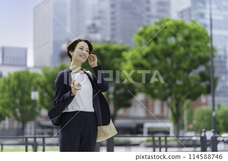 A businesswoman standing in an office district holding a tumbler 114588746