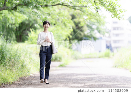 走在一條新鮮的綠色路的一個年輕女商人 114588909