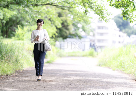 A young business woman walking on a fresh green road A young business woman walking on a fresh green road 114588912