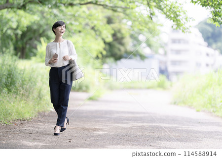 A young business woman walking on a fresh green road A young business woman walking on a fresh green road 114588914