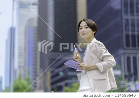 A businesswoman in an office district holding a pen tablet A businesswoman in an office district holding a pen tablet 114589640