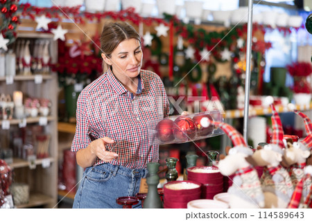 Girl buyer dreams of merry Christmas holiday and buys souvenirs to relatives and friends. Girl buyer dreams of merry Christmas holiday and buys souvenirs to relatives and friends. 114589643