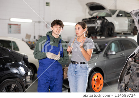 Guy car repair shop worker consulting woman client 114589724