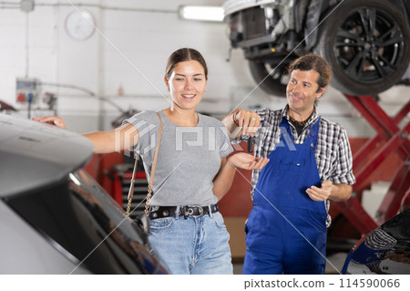 Male mechanic giving car keys to woman client 114590066