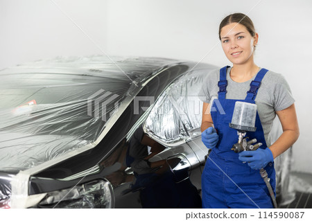 Young woman mechanic paints car with machine Young woman mechanic paints car with machine 114590087