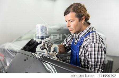 Repairman painter hand in protective glove with airbrush pulverizer painting car body Repairman painter hand in protective glove with airbrush pulverizer painting car body 114590192