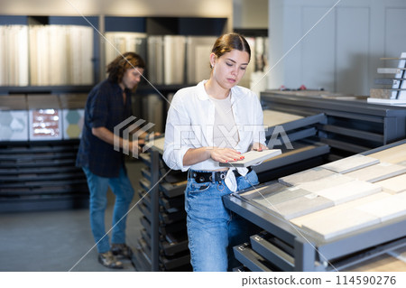 female buyer inspects small decorative tiles for redecorate apartment of new flat. Interior decor female buyer inspects small decorative tiles for redecorate apartment of new flat. Interior decor 114590276