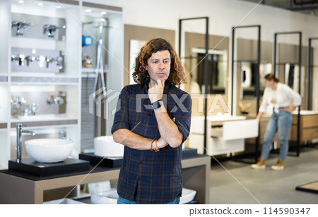 Focused man choosing what to buy in bathroom section of hardware shop Focused man choosing what to buy in bathroom section of hardware shop 114590347