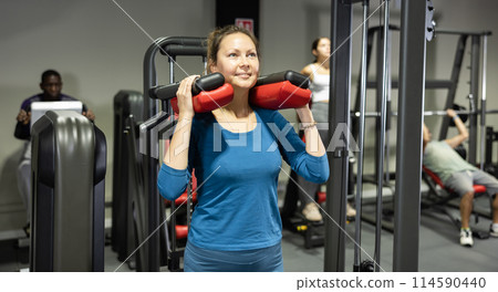 Young woman is engaged on simulator to strengthen muscles of legs in gym Young woman is engaged on simulator to strengthen muscles of legs in gym 114590440