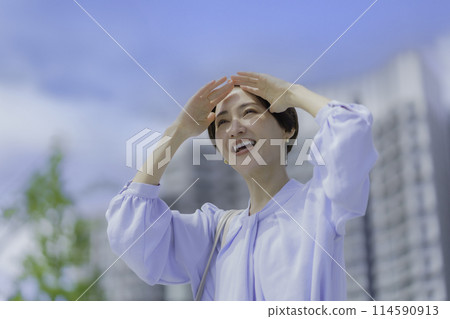 Middle-aged woman shielding her hands from the sun Middle-aged woman shielding her hands from the sun 114590913