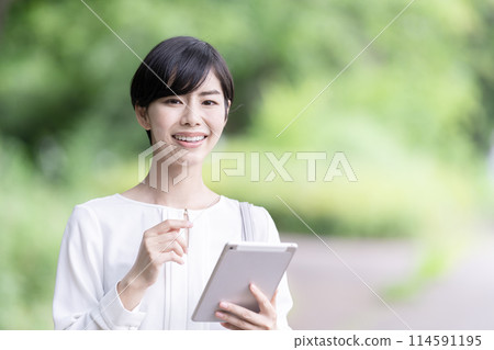 Business woman operating a tablet outdoors Young woman using a tablet 114591195