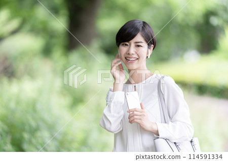 Young woman listening to music on her smartphone outdoors 114591334