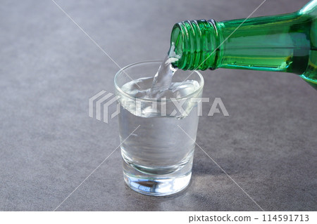 將韓國傳統蒸餾酒燒酒倒入玻璃杯中 將韓國傳統蒸餾酒燒酒倒入玻璃杯中 114591713
