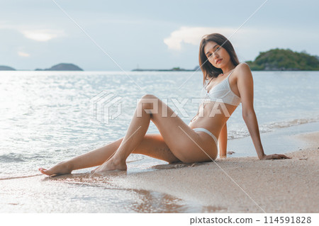 woman is laying on the beach in a bikini 114591828