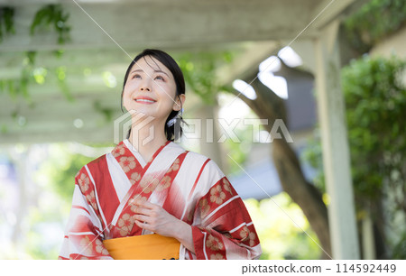 Beautiful Japanese woman wearing yukata outdoors in greenery, looking up Beautiful Japanese woman wearing yukata outdoors in greenery, looking up 114592449