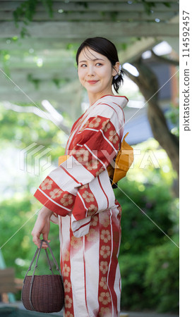 A woman wearing a yukata outdoors in the greenery, a beautiful woman looking back, vertical A woman wearing a yukata outdoors in the greenery, a beautiful woman looking back, vertical 114592457