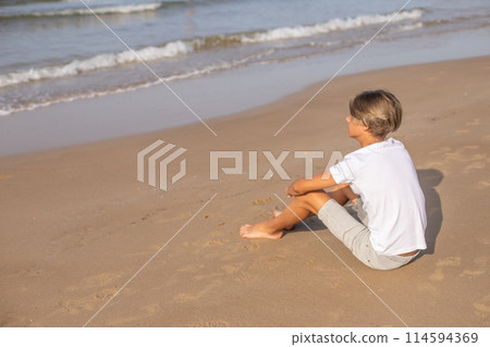 Handsome teenager boy sitting at the beach and enjoy a summer vacation. 114594369