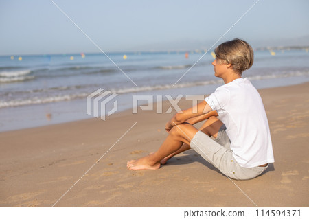 Handsome teenager boy sitting at the beach and enjoy a summer vacation. 114594371
