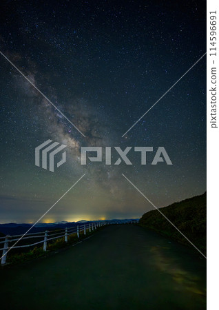 A night road with the Milky Way shining, and a view beyond the mountains 114596691