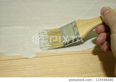 Close up of woman hand with paint brush painting old wooden table. Furniture renovation, diy and home improvement. Renewing restyling old fashioned furniture. Sustainable lifestyle, zero waste concept Close up of woman hand with paint brush painting old wooden table. Furniture renovation, diy and home improvement. Renewing restyling old fashioned furniture. Sustainable lifestyle, zero waste concept 114596886