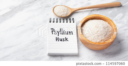 Psyllium husk in wood bowl and spoon with psyllium husk word on notebook on white marble table, copy space 114597060
