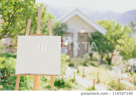 Painting canvas on wood stand outdoor with blur green nature house mountain view background 114597140