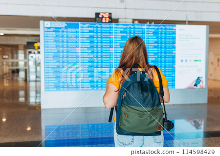 Redhead 30s Woman with backpack and camera looking at information board, rear view. Tourist journey trip concept Redhead 30s Woman with backpack and camera looking at information board, rear view. Tourist journey trip concept 114598429