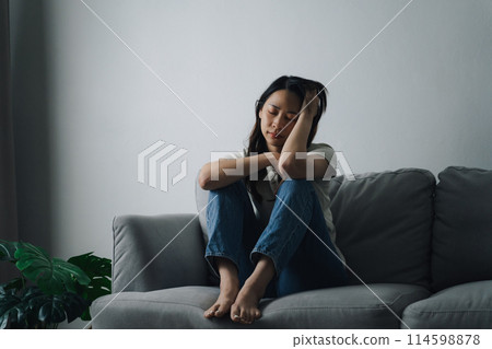 Unhappy lonely depressed woman is sitting on the couch and holding her head. Unhappy lonely depressed woman is sitting on the couch and holding her head. 114598878