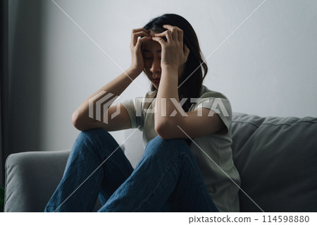 Unhappy lonely depressed woman is sitting on the couch and holding her head. Unhappy lonely depressed woman is sitting on the couch and holding her head. 114598880