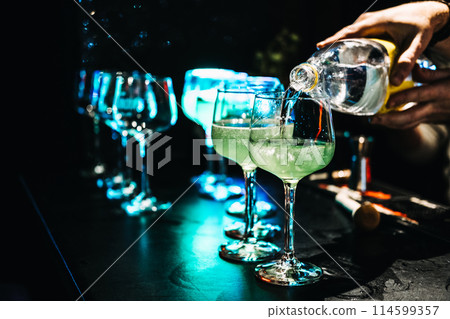 Pouring Tonic into Green Cocktails at a Vibrant Bar Pouring Tonic into Green Cocktails at a Vibrant Bar 114599357