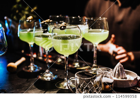 Green Cocktails Served at a Bustling Nighttime Bar 114599358