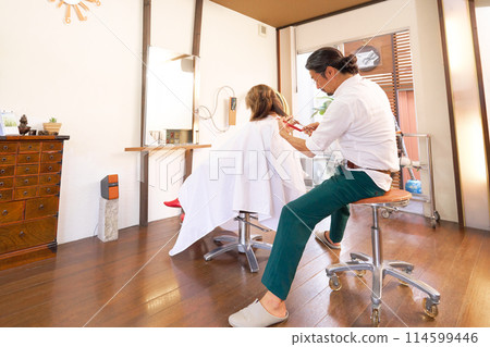 A veteran male hairdresser and a female customer undergoing treatment while sitting down A veteran male hairdresser and a female customer undergoing treatment while sitting down 114599446