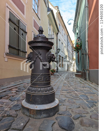 Bollard to restrict the movement of cars, decorative column on sidewalk of city street. The pole are on a on footpath in old town of Riga, Latvia. Bollard to restrict the movement of cars, decorative column on sidewalk of city street. The pole are on a on footpath in old town of Riga, Latvia. 114600100
