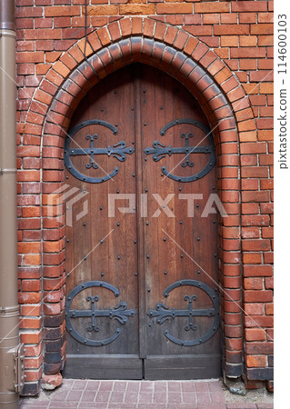 Old vintage wooden gothic door on a medieval building facade. 114600103