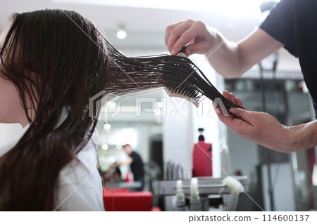 Wet hair is calculated with a comb. Hair care in a beauty salon. A woman with long, dark, matted hair. Wet hair is calculated with a comb. Hair care in a beauty salon. A woman with long, dark, matted hair. 114600137