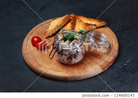 Homemade turkey or chicken liver pate in a glass jar. Baguette slices. Cherry tomatoes on a wooden round board. Homemade turkey or chicken liver pate in a glass jar. Baguette slices. Cherry tomatoes on a wooden round board. 114600145