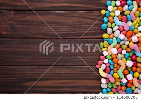 Colorful lollipops and different colored round candy on brown wooden background Colorful lollipops and different colored round candy on brown wooden background 114600706