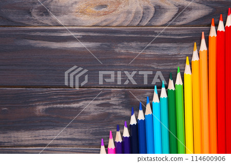 Many different colored pencils on brown wooden background 114600906
