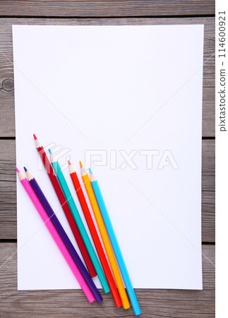 Many different colored pencils with white paper on grey wooden background Many different colored pencils with white paper on grey wooden background 114600921