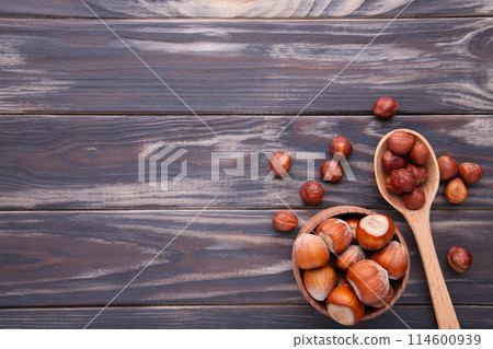 Delicious hazelnut in the wooden bowl and spoon on brown background Delicious hazelnut in the wooden bowl and spoon on brown background 114600939